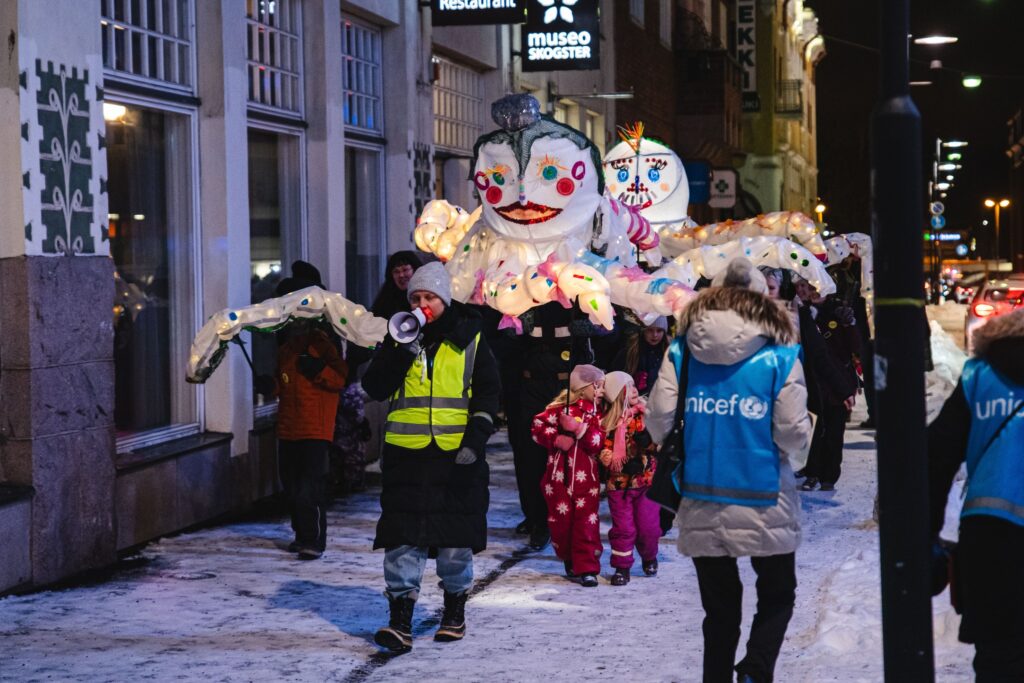 Valokaravaani, jossa ensimmäisenä kulkevat jättiläisvalonuket.